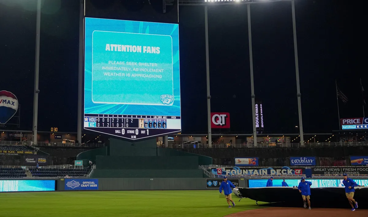 The grounds crew brings out the tarp at Kauffman Stadium in Kansas City, Missouri, where fans were advised to seek shelter as severe weather, June 13, 2026, delays the game between the Royals and the Houston Astros.