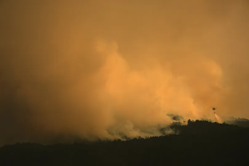 A firefighting helicopter drops water on the flames as a wildfire advances near Condemios de Arriba, Guadalajara province, Spain