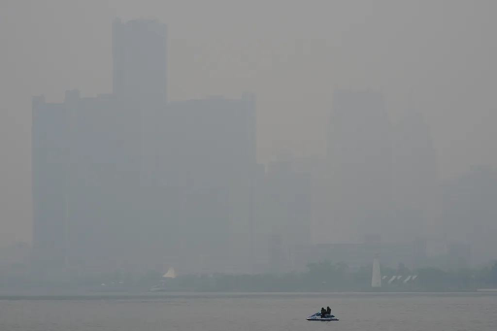 A watercraft sits in the Detroit River near the skyline during poor air quality due to smoke from Canadian wildfires Thursday, J