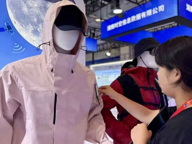 A staff member takes a Beidou short-message terminal out of the outdoor jacket.